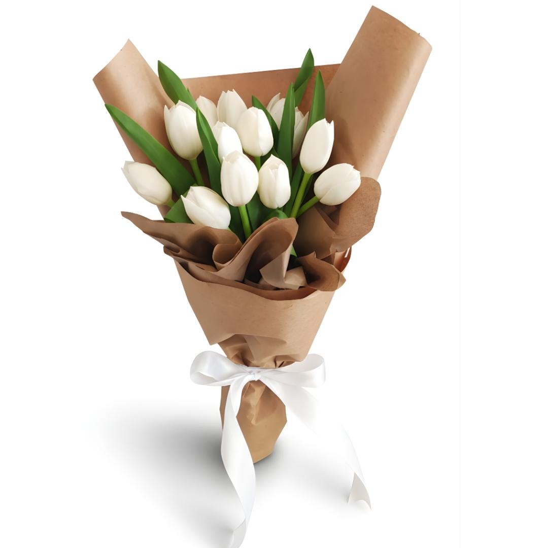 Bouquet of white tulips wrapped in brown paper with a white ribbon on a white background