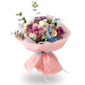 Bouquet of flowers wrapped in pink paper with a blue ribbon on a white background