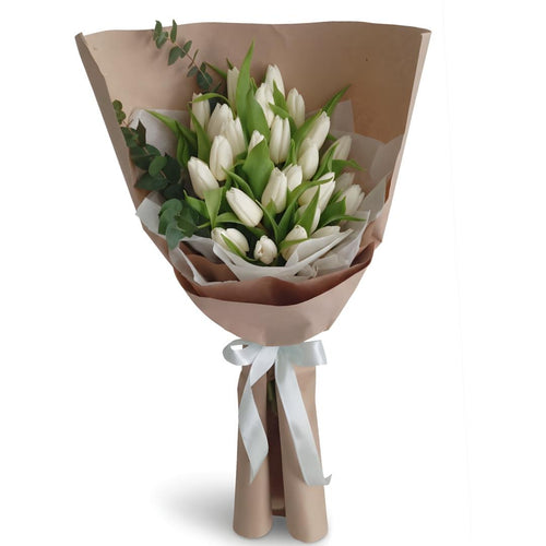 Bouquet of white tulips wrapped in brown paper with a white ribbon on a white background