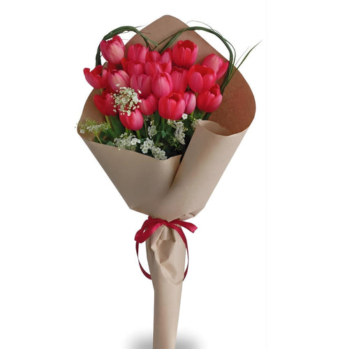 Bouquet of pink tulips wrapped in brown paper with a red ribbon on a white background