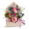 Floral arrangement in a decorative box with a pink ribbon on a white background