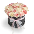 Black box with pink and white roses and a bow on a white background
